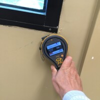 A person holds a mold detector against a wall